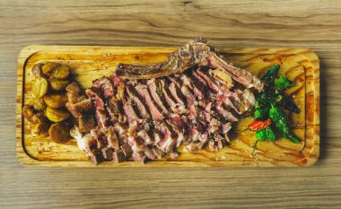 Sulu ve iştah açıcı dilimlenmiş biftek, patates ve Padron biberi. İspanyol Chuleton de Ternera. Ahşap kesme tahtasında ızgara et. En üst görüntü 