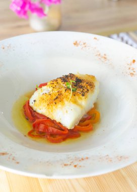 Ahşap masada kavrulmuş kırmızı biberli nefis pişmiş morina balığı..