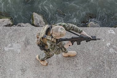 Askeri üniformalı asker, saldırı tüfeğiyle. Askeri teçhizat, ordu miğferi ve askeri harekat.