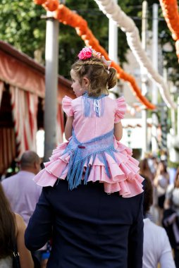 Seville, İspanya - 09 Mayıs 2019: Nisan Fuarı 'nda babasının omuzlarında oturan küçük kız (Feria de Abril), Sevilla Fuarı (Feria de Sevilla), Endülüs, İspanya