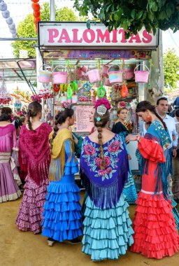 Seville, İspanya - 09 Mayıs 2019: Seville, İspanya - 09 Mayıs 2019: Geleneksel flamenko elbise giyen ve Nisan Fuarı 'nda (Feria de Abril) alışveriş yapan kızlar, Sevilla Fuarı (Feria de Sevilla), Endülüs, İspanya