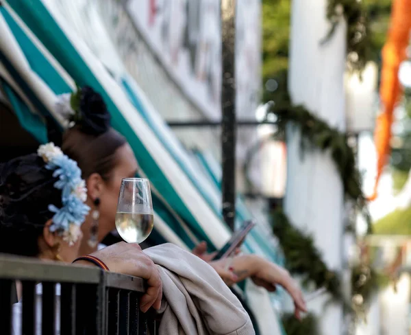 Nisan Fuarı 'nda (Feria de Abril), Sevilla Fuarı' nda (Feria de Sevilla), Endülüs 'te el ele tutuşan beyaz şarap kadehi. Seyahat ve turizm kavramları. Seçici odak.