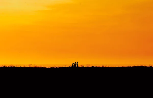 Family silhouette having fun on the beach at the sunset time. Concept of friendly family and of summer vacation