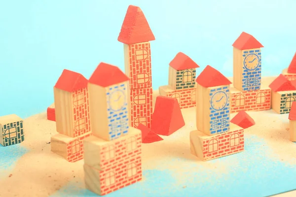 Mavi arka planda tahta blokları olan oyuncak bir bina..