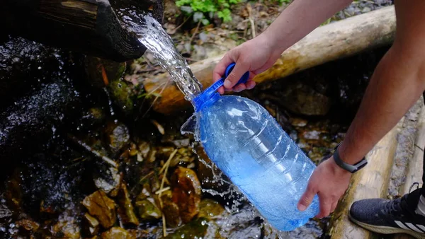 Kaynak suyu, bir adam kaynak suyu çekiyor, bir dağ pınarından kristal berrak su.