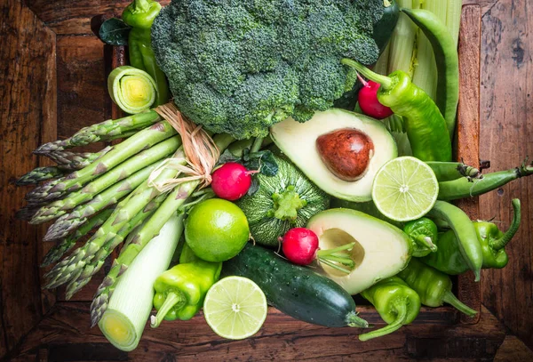 Fresh organic green vegetables and fruits on dark wooden background.Vegan food, green diet concept.