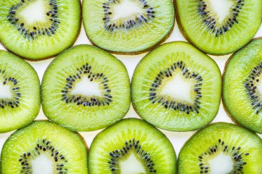 Kivi meyveleri düz arkaplanda yatıyor. Yeşil dilimler kivi meyveleri arka planda..