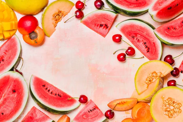 Summer fruits watermelon and melon, peaches, cherries frame copy space background vibrant colors.