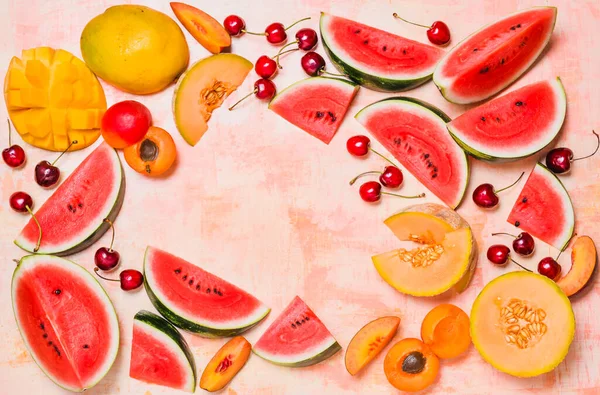 Summer fruits watermelon and melon, peaches, cherries frame copy space background vibrant colors.