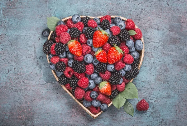 Berries and fruits heart shaped top view copy space background.