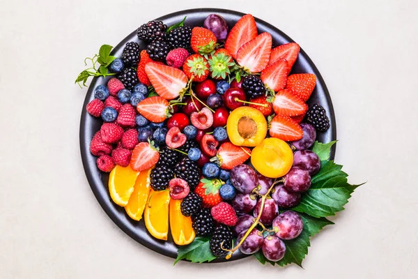 Fruits and berries assortment in plate copy space background.Healthy colorful delicious snack.