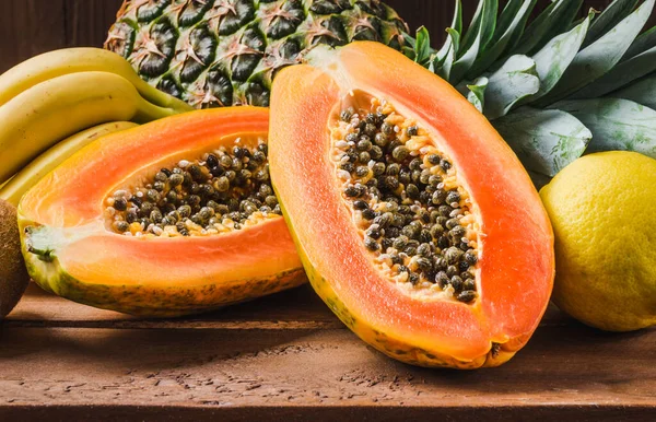 Papaya, ananas tropical fruits on wooden background.