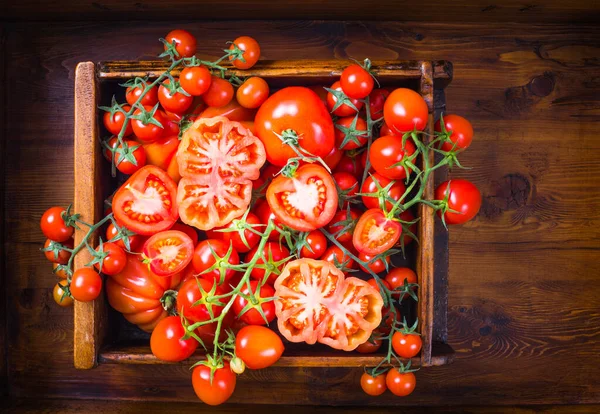 Red tomatoes on wooden background copy space.