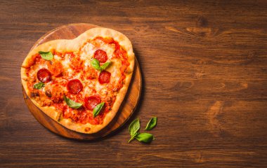 Pizzanın kalbi ahşap arka plan fotokopi alanında pizza şeklinde. Lezzetli İtalyan pizza teslimat menüsü.