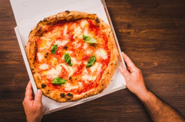 Tahta arka planda pizza. Kopya uzay teslimat menüsü konsepti. Elleri pizza tutuyor..