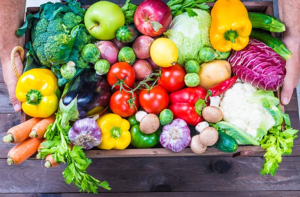 Delivery of fresh organic vegetables and fruits, local food organic market.Hands holding box with vegetables and fruits background copy space.