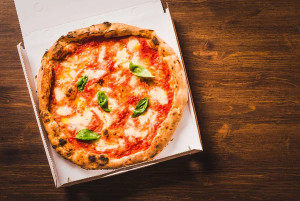Pizza on wooden background copy space.True delicious Italian pizza delivery menu concept.