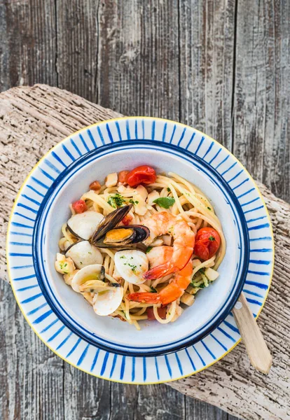 Pasta with mussels, clams, shrimps on wooden table top view. Typical Italian food spaghetti allo scoglio.