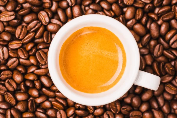Cup of espresso coffee and coffee beans background. Traditional Italian cup of coffee at bar.