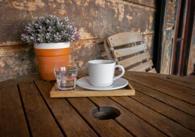 Beyaz kahve fincanı ve bir bardak su eski ahşap masa ve saksı