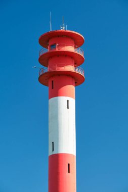Vertical shot of red and white lighthouse with blue sky in background