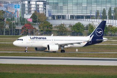Lufthansa Bölgesel Jeti, Almanya 'nın Münih Havaalanı terminalindeki park halindeki uçağın önünde kalkıyor..