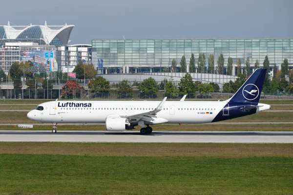 Lufthansa Airbus A321 Münih Havaalanı 'ndan bir iş binasının önünde kalkıyor.