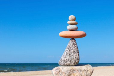Plajda beyaz ve pembe çakıl taşı piramidi. Denge, uyum ve meditasyon kavramı