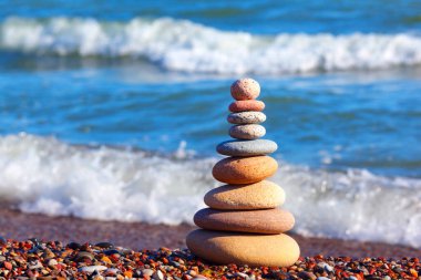 Yaz denizinin arka planında renkli çakıl taşları piramidi. Uyum, denge ve meditasyon kavramı
