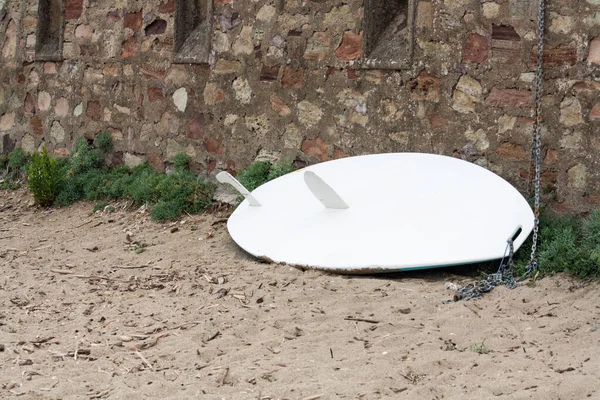 Duvara yaslanmış kullanılmamış bir sörf tahtası.