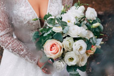 Büyük bir düğün buketi beyaz sarı ve pembe güllerden oluşan güzel bir gelinin ellerinde. Yüzü olmayan bir tatilde sokakta yakası açık bir elbise içinde.