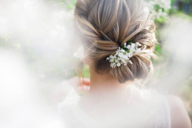 Yeşil yapraklı, çiçek açan bahar bahçesinde sarışın bir gelin için örgü ören sanat eserleri.