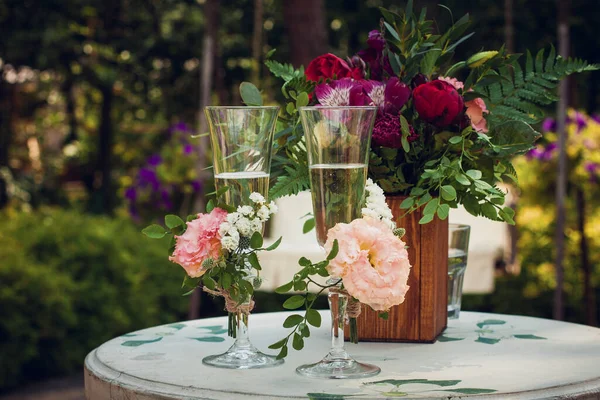 在一个夏日的花园 在一个婚宴上 在一个装饰着白色 粉色和红色花朵的木制褐色花瓶的白色木制桌子上 在一个新婚夫妇的婚宴上 喝着香槟酒的玻璃杯 — 图库照片
