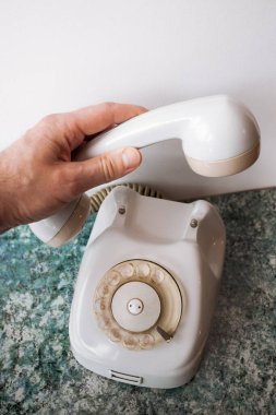 Bir el telefonu eski bir analog beyaz Sovyet telefonundan alıyor mavi desenli bir masa üstü ve beyaz bir arka plan üzerinde..