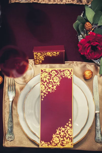 桌子上的构图由餐具 白盘和红金相间的节日卡片组成 桌子上装饰着花和金黄的核桃 — 图库照片