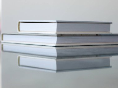 Beyaz ve bej renkli iki kapalı fotobook 'un makro fotoğrafı parlak desenli mavi bir masanın üzerinde yatıyor..