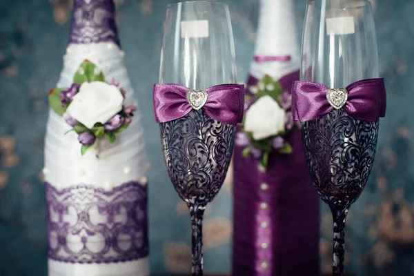 新娘和新郎的一对装饰用紫色香槟酒瓶和眼镜站在一个房间里 背景是蓝色的壁纸 — 图库照片