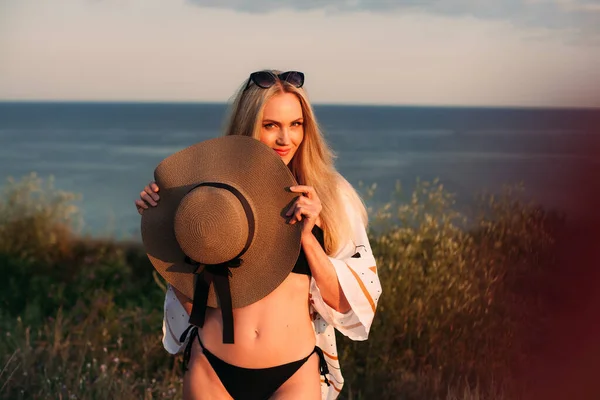 비키니 수영복을 안경을 매력적 미소짓는 소녀가 금발의 머리를 모자를 석양에 — 스톡 사진
