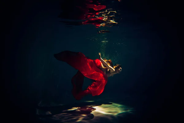 艺术品 一名身穿内衣的女运动员在水底拍摄的照片 她穿着红色的内衣 游泳池里有漂亮的亮点 — 图库照片