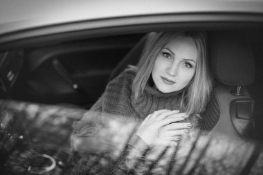 Sanat eserleri. Güzel, şık bir kızın arabada otururken çekilmiş siyah beyaz bir fotoğrafı. Arabanın camlarında güzel yansımalar var..