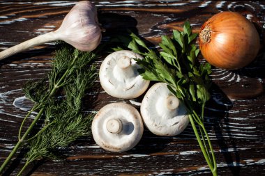 Şampiyonların yaratıcı kompozisyonu, sarımsak, soğan, otlarla, dereotuyla ve maydanozla süslenmiş, koyu dokulu ahşap arka planda..