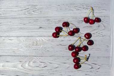 Olgun kırmızı kirazlar gün boyunca açık dokulu ahşap bir masada yatar..