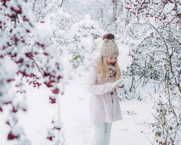 一个漂亮的年轻姑娘 金发碧眼 穿着浅色的毛衣和围巾 笑着站在雪地里 站在冬季的森林里 在树的枝头周围 — 图库照片