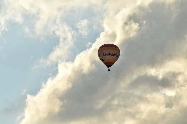 Hot air balloon and a beautiful sky with many clouds in the background. The balloon says 