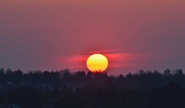 Büyük güneş ufukta batar. Sisin içinde renkli gün batımı.