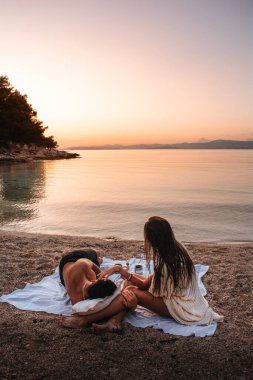 Il 'de kumsalda gün batımını izleyen bir çift. Brac, Hırvatistan.