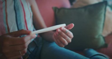 Genç bir kadının hamilelik testini evdeki kanepede çekerken görüntüsü. Yüksek kalite 4k görüntü