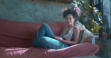 Güzel bir Afrikalı genç kadının akıllı telefonuyla evde dinlendiği bir fotoğraf. Yüksek kalite 4k görüntü