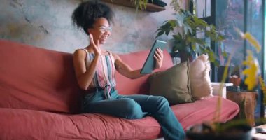 Oturma odasındaki video görüşmesi için dijital tablet kullanan genç ve güzel bir kadının görüntüsü. Yüksek kalite 4k görüntü