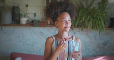 Oturma odasında ilaç içen güzel bir Afrikalı kadın fotoğrafı. Yüksek kalite 4k görüntü